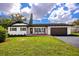 Well-manicured front yard featuring a white home with dark trim, and a lush lawn at 1873 Murray Ave, Clearwater, FL 33755