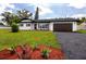 Charming single-story home with a well-maintained lawn, black asphalt driveway, and manicured landscaping at 1873 Murray Ave, Clearwater, FL 33755