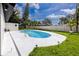 A backyard pool features a spacious white patio, tropical landscaping and perimeter lighting at 1873 Murray Ave, Clearwater, FL 33755