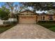 Wide shot of garage exterior featuring paver driveway, trellis with vines, and lush landscaping at 213 N Hesperides St, Tampa, FL 33609
