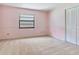 Empty bedroom with pink walls, white trim, and a window at 2217 High Point Dr, Brandon, FL 33511