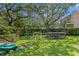 Landscaped backyard features playground, swing set, trampoline, and shade trees for outdoor enjoyment at 2403 W Sunset Dr, Tampa, FL 33629