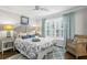 Comfortable bedroom featuring patterned bedding, natural light, ceiling fan, and a wicker chair at 2403 W Sunset Dr, Tampa, FL 33629