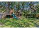 Fun backyard playground with a playhouse, slide, swings, climbing dome, and lush green grass at 2403 W Sunset Dr, Tampa, FL 33629