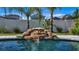 Beautiful swimming pool with a captivating rock waterfall feature, surrounded by lush landscaping at 28809 S Orange Berry S Dr, Wesley Chapel, FL 33543
