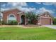 Single-story home featuring a manicured lawn, brick walkway, and a two-car garage at 29650 Eagle Station Dr, Wesley Chapel, FL 33543