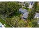 Aerial view of home showing well-manicured lawn, a quaint porch, and surrounded by mature trees at 3404 W Leona St, Tampa, FL 33629