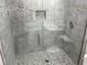 Modern bathroom shower featuring decorative pebble floor and accent tiles, a glass door, and tiled walls at 3718 N 36Th St, Tampa, FL 33610