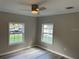 Cozy bedroom with gray walls, gray flooring, two windows, and modern ceiling fan with light at 3718 N 36Th St, Tampa, FL 33610