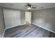 This bedroom features modern gray wood floors, a ceiling fan, neutral walls, and a spacious closet for ample storage at 3718 N 36Th St, Tampa, FL 33610