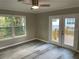 Bright bedroom featuring gray wood floors, a ceiling fan, and access to an outdoor deck through elegant glass doors at 3718 N 36Th St, Tampa, FL 33610