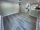 Open-concept living room showcasing gray wood-look flooring connecting to the kitchen and bright lighting at 3718 N 36Th St, Tampa, FL 33610