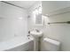 Well-lit bathroom features a tiled shower-tub, pedestal sink, and classic black and white tiled floor at 3919 W Paxton Ave, Tampa, FL 33611
