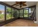 Bright sunroom with light wood flooring, ceiling fan, and screened windows showcasing natural views at 4039 La Pasida Ln, New Port Richey, FL 34655