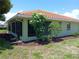 The exterior of a cozy, light green home featuring a red tile roof and screened-in lanai at 405 Lemonwood Dr, Englewood, FL 34223