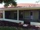 Back screened-in lanai with exterior door, tidy mulch bed and part of a red tile roof visible at 405 Lemonwood Dr, Englewood, FL 34223