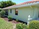 Exterior side shot of a green single-story home with a red tile roof, trimmed landscaping at 405 Lemonwood Dr, Englewood, FL 34223