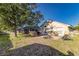 A sunny backyard featuring a patio with chairs, a barbecue grill, and a partial view of the screened-in pool at 447 Bridle Path Way, Tarpon Springs, FL 34688