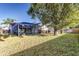 A large backyard featuring an enclosed pool area with a screen enclosure with a sprawling green lawn at 447 Bridle Path Way, Tarpon Springs, FL 34688