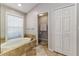 This bathroom features a soaking tub, a window, and an entrance to a separate toilet area at 447 Bridle Path Way, Tarpon Springs, FL 34688