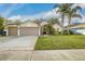 Charming single-story home features a well-manicured lawn, mature palm trees and a two-car garage at 447 Bridle Path Way, Tarpon Springs, FL 34688