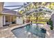 This screened-in pool has brick pavers, mature landscaping, and a view of the backyard at 447 Bridle Path Way, Tarpon Springs, FL 34688
