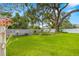Large, green backyard featuring a giant tree, garden, and white fencing on a sunny day at 5800 3Rd S St, St Petersburg, FL 33705
