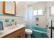 Bright bathroom with wood-look cabinets and marble counters plus blue tile backsplash and trim at 5800 3Rd S St, St Petersburg, FL 33705