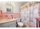 Clean, pink bathroom with a white vanity and a seashell-patterned shower curtain at 5800 3Rd S St, St Petersburg, FL 33705