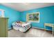 Bright blue bedroom with light carpet, a window and bed with colorful floral patterned covers at 5800 3Rd S St, St Petersburg, FL 33705