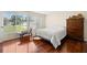 Bedroom with shiny wood floors, dresser, bedside table, and natural light from a large window at 5800 3Rd S St, St Petersburg, FL 33705
