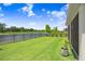 Enjoy a spacious backyard with lush green grass, a view of the pond, and mature landscaping at 6097 Golden Nettle Dr, Apollo Beach, FL 33572