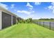 Expansive backyard with manicured lawn, fence, and serene lake views at 6097 Golden Nettle Dr, Apollo Beach, FL 33572