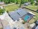 Aerial view of home featuring a screened pool, patio, and large concrete driveway with multiple storage buildings at 6219 Wendell Dr, Wesley Chapel, FL 33544