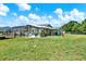 Expansive backyard with lush lawn, screened-in patio, mature trees, and privacy fencing at 6219 Wendell Dr, Wesley Chapel, FL 33544