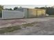 Wide metal building with roll-up doors, attached shed and large concrete parking lot at 6219 Wendell Dr, Wesley Chapel, FL 33544