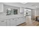 Bright kitchen featuring white cabinets, subway tile backsplash, and wood flooring at 6310 Gainsboro Ave, Spring Hill, FL 34609