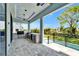 A covered patio features an outdoor kitchen and views of the yard and adjacent in-ground pool at 6530 Simone Shores Cir, Apollo Beach, FL 33572