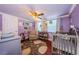 Cozy Bedroom featuring hardwood floors, soft lighting and a ceiling fan with a crib and a rocking chair at 6618 N 11Th St, Tampa, FL 33604