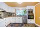This kitchen features white cabinets, stainless steel appliances, and a stylish mosaic backsplash at 6618 N 11Th St, Tampa, FL 33604