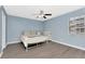 Main bedroom features a ceiling fan, large window and gray wood floors at 6817 Stones Throw N Cir # 17203, St Petersburg, FL 33710