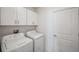 Efficient laundry room with white appliances, upper cabinets and access door at 71 Rose Bud Ln, Spring Hill, FL 34609