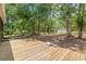 Spacious backyard and deck featuring lush, mature trees and an outbuilding with rolling doors at 7644 Conrad St, Wesley Chapel, FL 33544