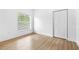 Empty bedroom featuring wood look floors, a window with blinds, and a closet with bi-fold doors at 7644 Conrad St, Wesley Chapel, FL 33544