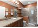 Bathroom with double vanity, framed mirror, tiled walk-in shower, brown walls, and decorative lighting at 918 Sombra Street, Tampa, FL 33619