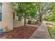 Side view of a townhome with beige siding, a landscaped yard, and a sidewalk at 918 Sombra Street, Tampa, FL 33619
