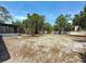 Large backyard with trees, partial fence, sandy ground cover, and screened-in porch at 922 Alcazar S Way, St Petersburg, FL 33705