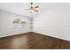 Spacious bedroom featuring wood-look flooring, ceiling fan, window, and three decorative wall shelves at 10900 Livingston Dr, New Port Richey, FL 34654