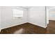 Neutral bedroom showcases dark wood-look floors, a bright window, and crisp white trim at 10900 Livingston Dr, New Port Richey, FL 34654