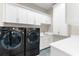 Well-equipped laundry room with modern washer, dryer, white cabinets, and unique tile floor at 110 Carlyle Dr, Palm Harbor, FL 34683